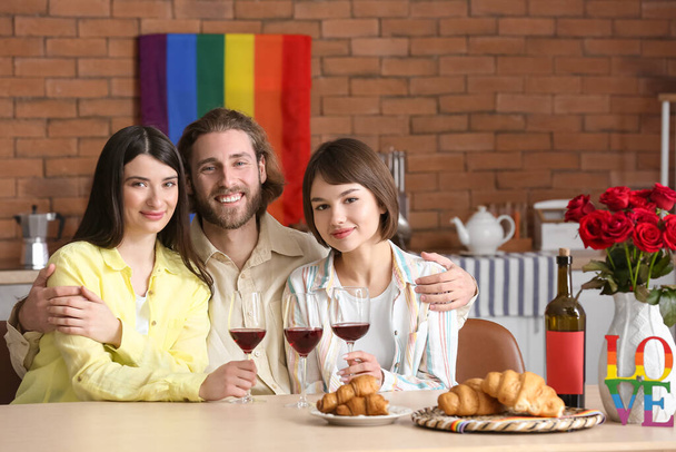 Hombre y dos mujeres hermosas bebiendo vino en casa. Concepto de poliamory - Foto, Imagen