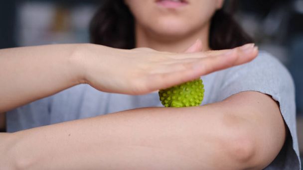 Detailní záběr mladé ženy cvičí svaly na pažích zeleným myofasciálním míčkem. Žena dělá cvičení s gumovou koulí - Fotografie, Obrázek