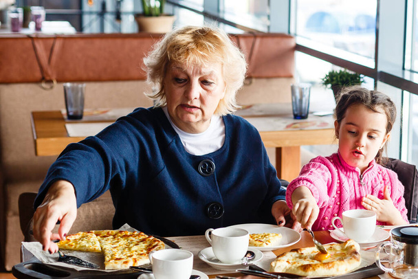infanzia e concetto di persone - nonna felice e bambina con cucchiaio mangiare al caffè all'aperto o al ristorante - Foto, immagini