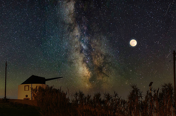 Νυχτερινό τοπίο με λαμπερό ουρανό με παλιό ανεμόμυλο - Φωτογραφία, εικόνα