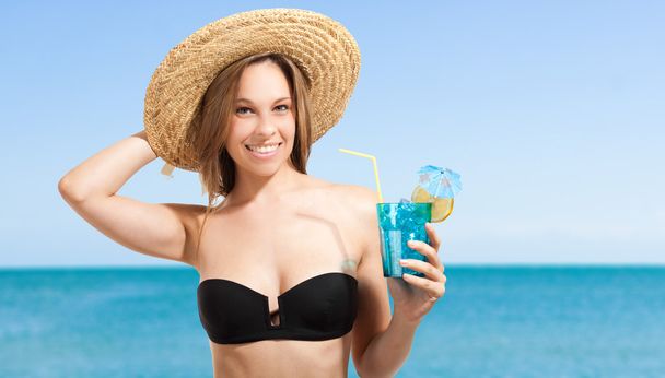 Vrouw drinkt cocktail op het strand - Foto, afbeelding