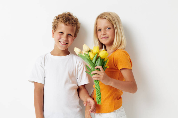 Boy and girl with a bouquet of flowers gift birthday holiday childhood light background - Foto, afbeelding