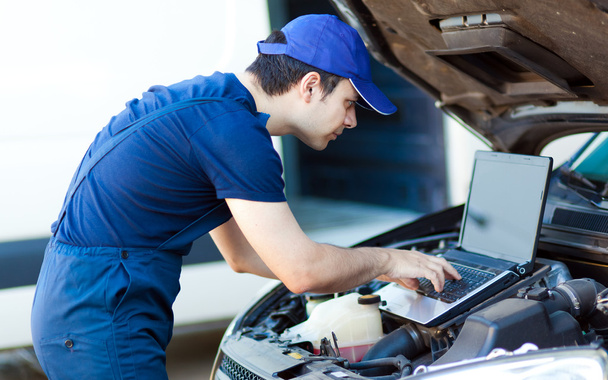 Mechanic using laptop to check car engine - Foto, Imagen