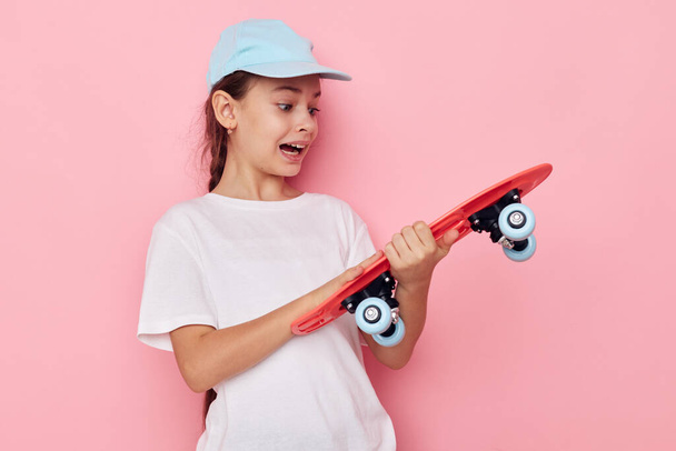 Portrait of happy smiling child girl cap in white t-shirt skateboard Lifestyle unaltered - Photo, Image