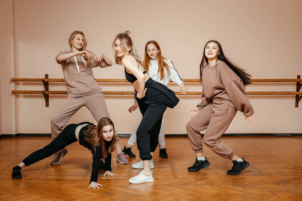 Сучасні танцюристи позують на тлі танцювальної студії, виконуючи елементи сучасного танцю, професійна група танцюристів готується до концерту
 - Фото, зображення