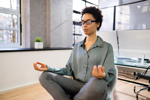 Young African Woman Sitting On Desk Meditating In Office - Foto, Bild
