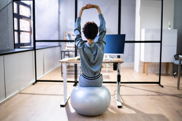 African American Employee Exercising On Ball In Office - Foto, imagen