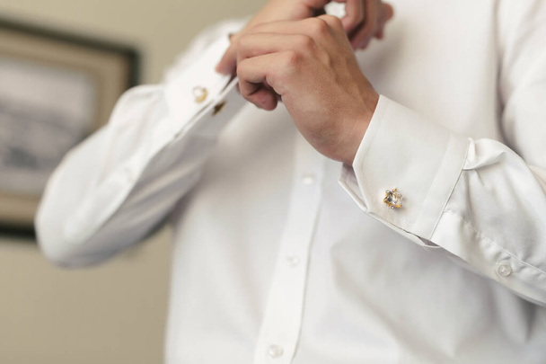 Men put on a shirt and fasten cufflinks on the morning of the wedding day - Foto, Bild