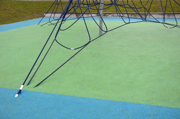 klimmen spel elementen in vlekken, kinderspeelplaatsen, zijn er tartan rubberen oppervlakken gemaakt van geplet rubber aan elkaar gelijmd. touw centrum met trampoline. handafdruk in bevroren vorst, smelten - Foto, afbeelding