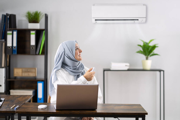 Happy Muslim Woman Working In Office With Air Conditioner - Фото, изображение