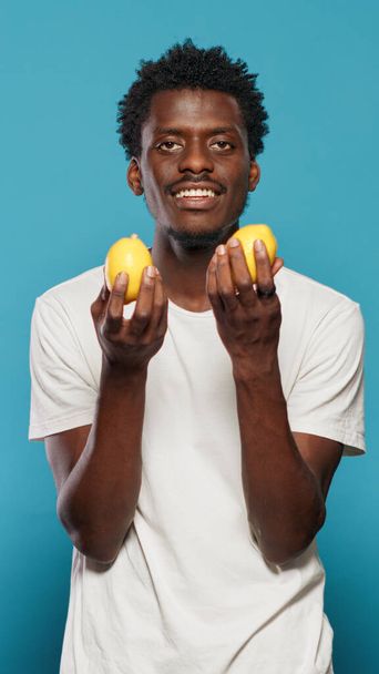 Χαρούμενο άτομο που κρατάει λεμόνια για υγιεινή χορτοφαγική διατροφή - Φωτογραφία, εικόνα