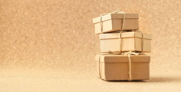 Картонні подарункові коробки прив'язані шпагатом на теплому коричневому фоні. Перероблена упаковка для збереження природи
. - Фото, зображення