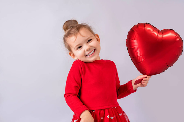 dziewczynka uśmiechnięta z nadmuchiwanym balonem w kształcie serca w ręku - Zdjęcie, obraz