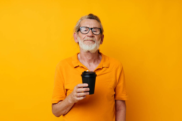 old man in a yellow T-shirt a glass with a drink monochrome shot - Zdjęcie, obraz