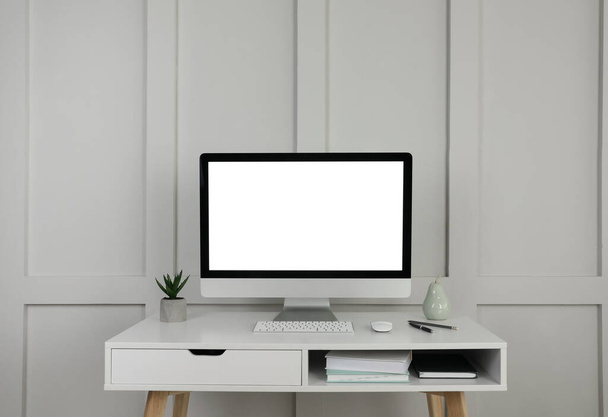 Nowoczesne wyposażenie komputerowe, dekoracyjne i biurowe na białym drewnianym stole przy ścianie - Zdjęcie, obraz