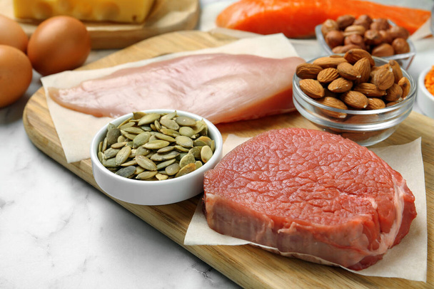 Fresh meat and other products on white table, closeup. Sources of essential amino acids - Fotografie, Obrázek