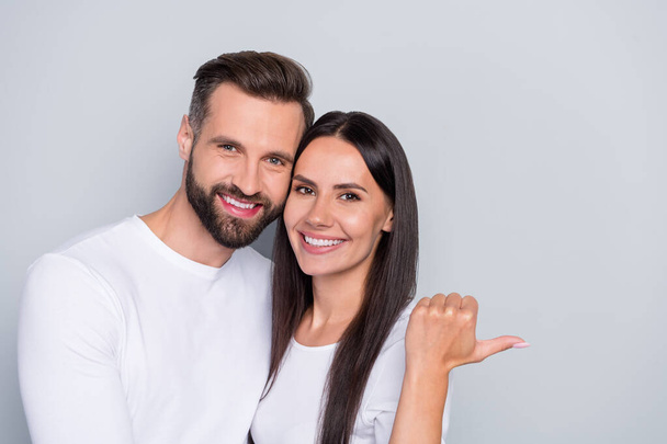 Portrait of attractive cheerful couple cuddling demonstrating copy blank space ad isolated over grey pastel color background - Φωτογραφία, εικόνα
