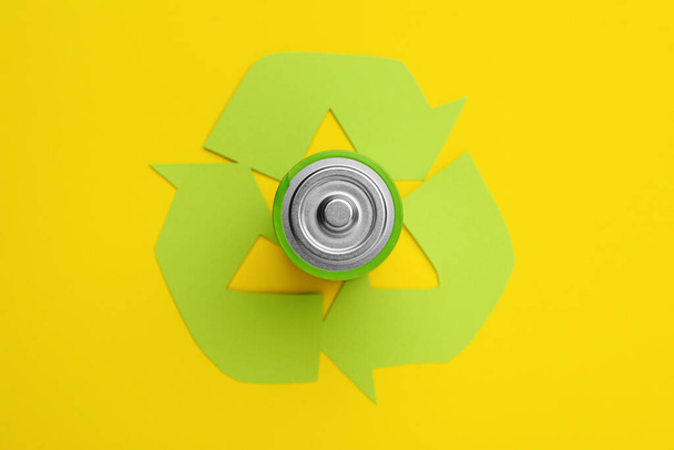 Used battery and recycling symbol on yellow background, top view - Fotografie, Obrázek