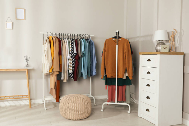 Racks with stylish clothes in cozy room interior. Fast fashion - Fotoğraf, Görsel