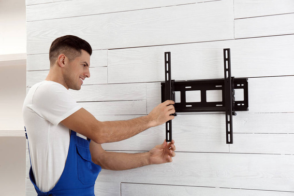 Professional technician installing TV bracket on wall indoors - Fotó, kép