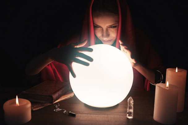 Soothsayer using glowing crystal ball to predict future at table in darkness. Fortune telling - Foto, immagini