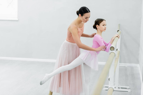 обучение стройных девушек в танцевальной студии рядом с молодым балетмейстером - Фото, изображение