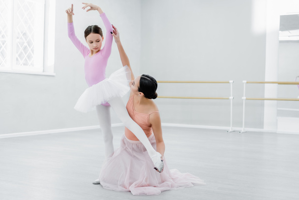 preteen fille pratiquant des éléments chorégraphiques près de jeune professeur de ballet - Photo, image