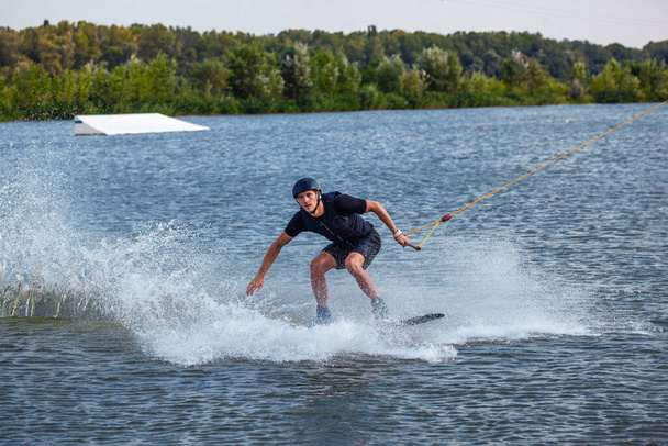 Człowiek balansowanie na wakeboard holowane na kablówce próbuje chwycić pokładzie - Zdjęcie, obraz