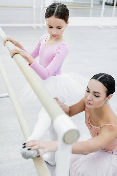 preteen girl stretching in ballet school near young dance teacher - Photo, Image