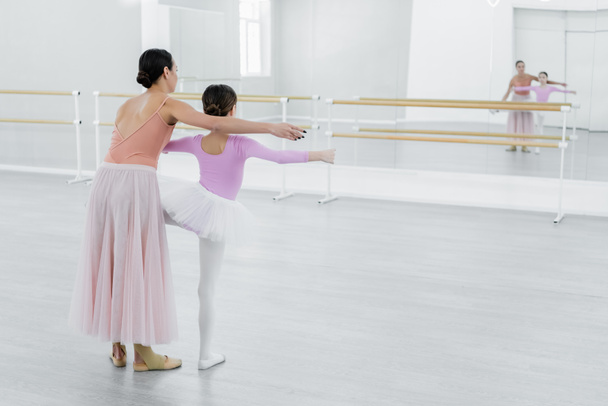 widok z tyłu dziewczyna szkolenia w szkole baletowej w pobliżu luster i młody nauczyciel tańca - Zdjęcie, obraz