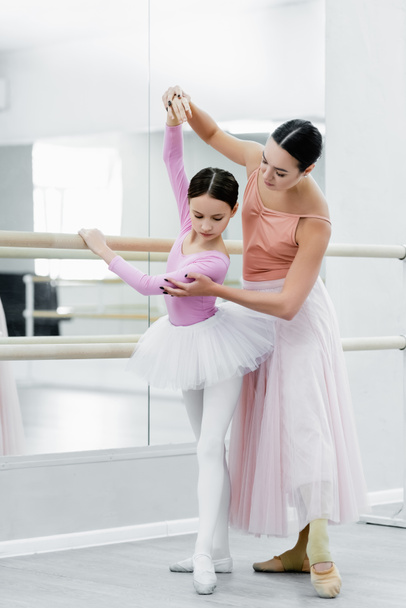вид в полный рост на тренировку девочки в школе балет рядом с молодым учителем танцев - Фото, изображение