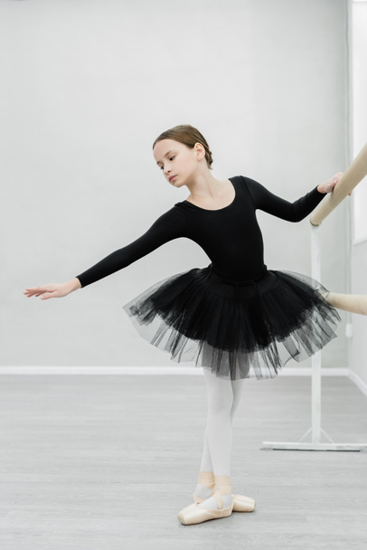 full length view of graceful girl in black ballet costume training in dancing hall - Photo, Image