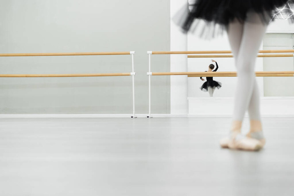 θολή κοπέλα χορεύει σε στούντιο μπαλέτου κοντά αντανάκλαση στον καθρέφτη στο παρασκήνιο - Φωτογραφία, εικόνα