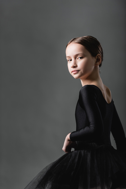 graceful girl in black ballet costume looking at camera on grey background - Zdjęcie, obraz