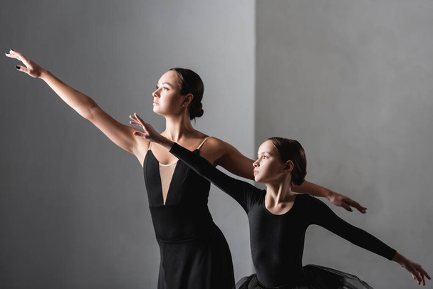 грациозный балетмейстер и девушка танцуют на сером фоне - Фото, изображение