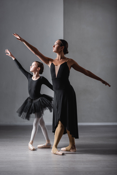 full length view of ballet teacher and girl in black tutu dancing during lesson - Фото, зображення