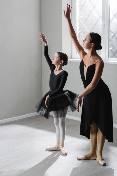 teljes hosszúságú kilátás lány tanul táncolni balett közelében kecses balerina - Fotó, kép
