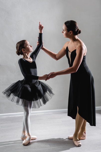 full length view of ballerina teaching girl to dance ballet in studio - Valokuva, kuva