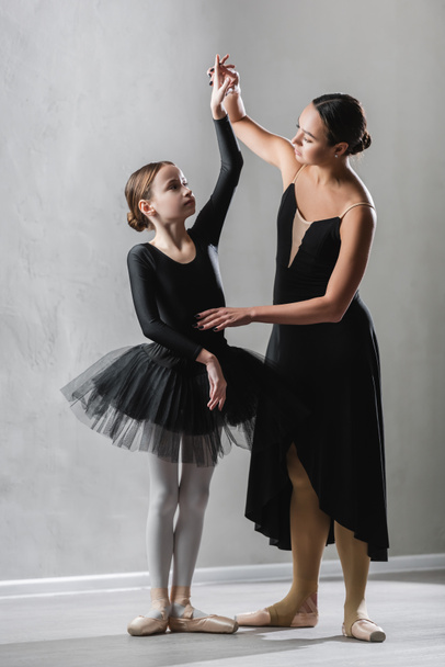 χαριτωμένη μπαλαρίνα σηκώνοντας το χέρι του κοριτσιού μαθαίνουν να χορεύουν μπαλέτο - Φωτογραφία, εικόνα