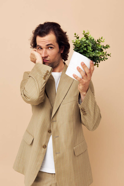 Elinde çiçek saksısı olan yakışıklı bir adam klasik izole edilmiş bir arka plan. - Fotoğraf, Görsel