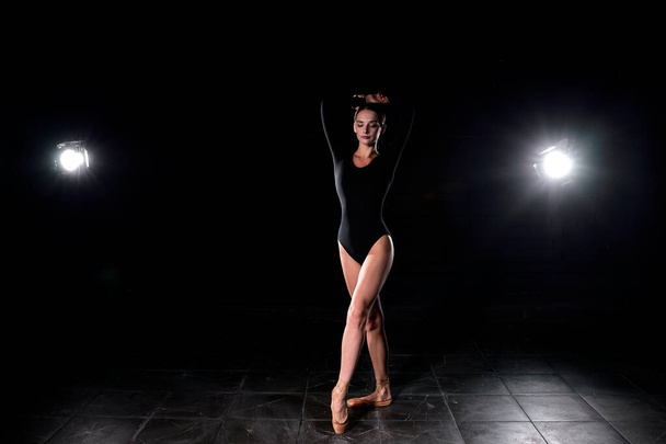 Beautiful Ballet Dancer Posing On Pointes. Ballerina Wearing Black Suit Is Going To Dance - Foto, imagen