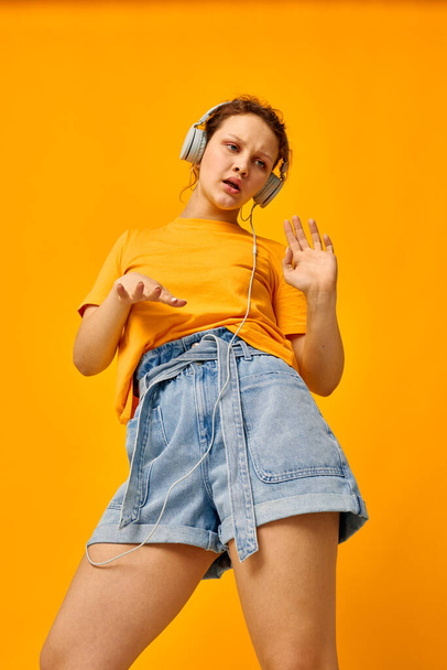 funny girl listening to music on headphones Youth style yellow background unaltered - Valokuva, kuva