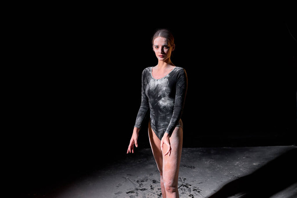Female ballet dancer gymnast in studio on black background, studio with flour - 写真・画像