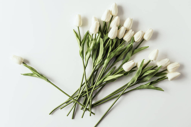 White tulips on white background. Valentines Day, Mothers day, Birthday, spring time. Celebration concept. Greeting card, template. Copy space, flat lay. - Photo, image