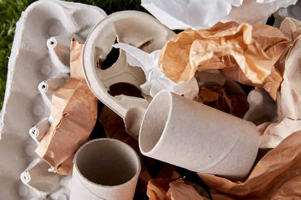 close up of crumpled paper waste on grass - Zdjęcie, obraz