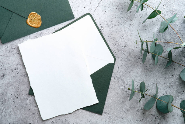Wedding stationery set. Wedding invitation card template, green envelope, eucalyptus branches on concrete background. Flat lay, top view, copy space. - Fotó, kép