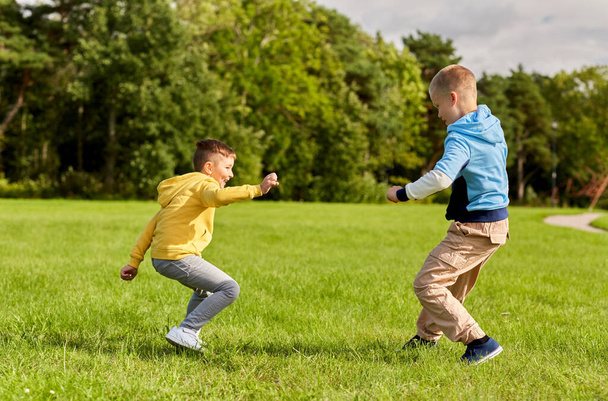 two happy boys playing tag game at park - Photo, Image