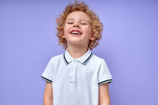 little curly child boy have fun, laughing smiling isolated on purple background - Foto, afbeelding