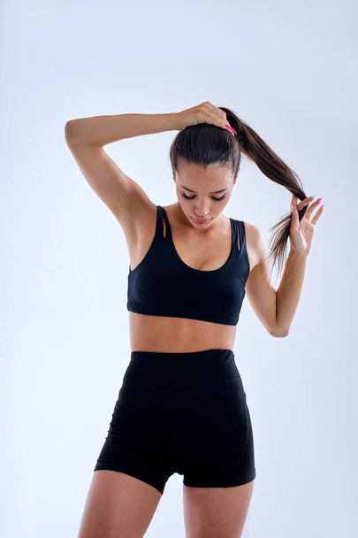 beautiful caucasian slim fitness woman making ponytail preparing for sport workout - Foto, afbeelding