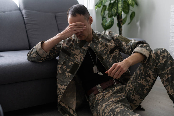 Depressed and sad soldier in green uniform with trauma after war. - Φωτογραφία, εικόνα